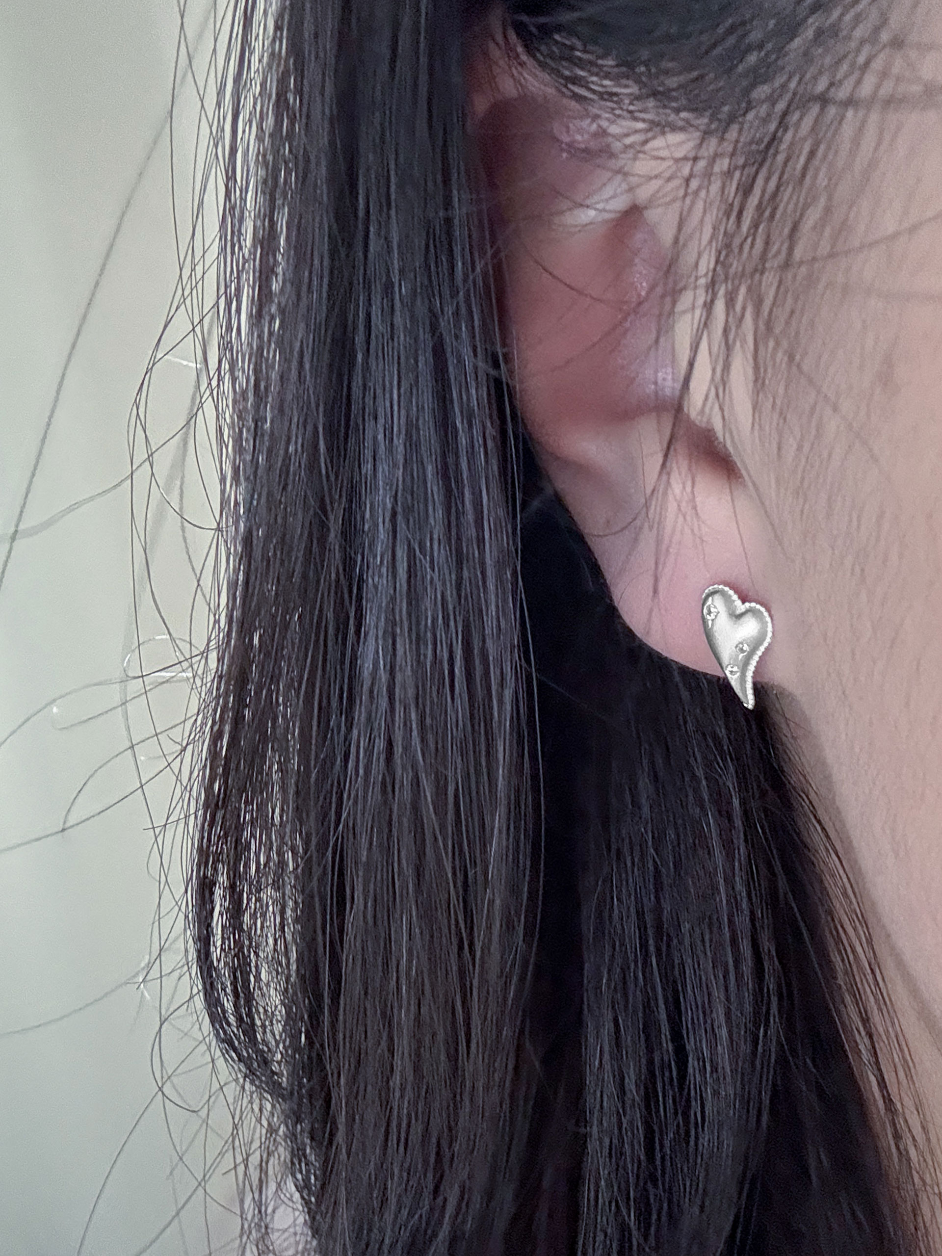 얼굴 가까이에서 착용한 cubic heart earring, 작은 사이즈지만 형태가 또렷하게 보이는 모습