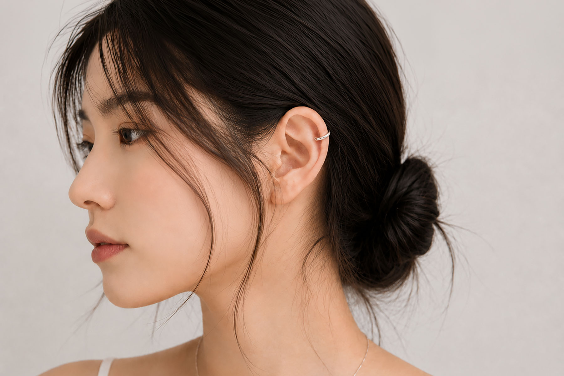 묶은 머리에 실버 이어커프를 착용한 귀 주변 레이어링